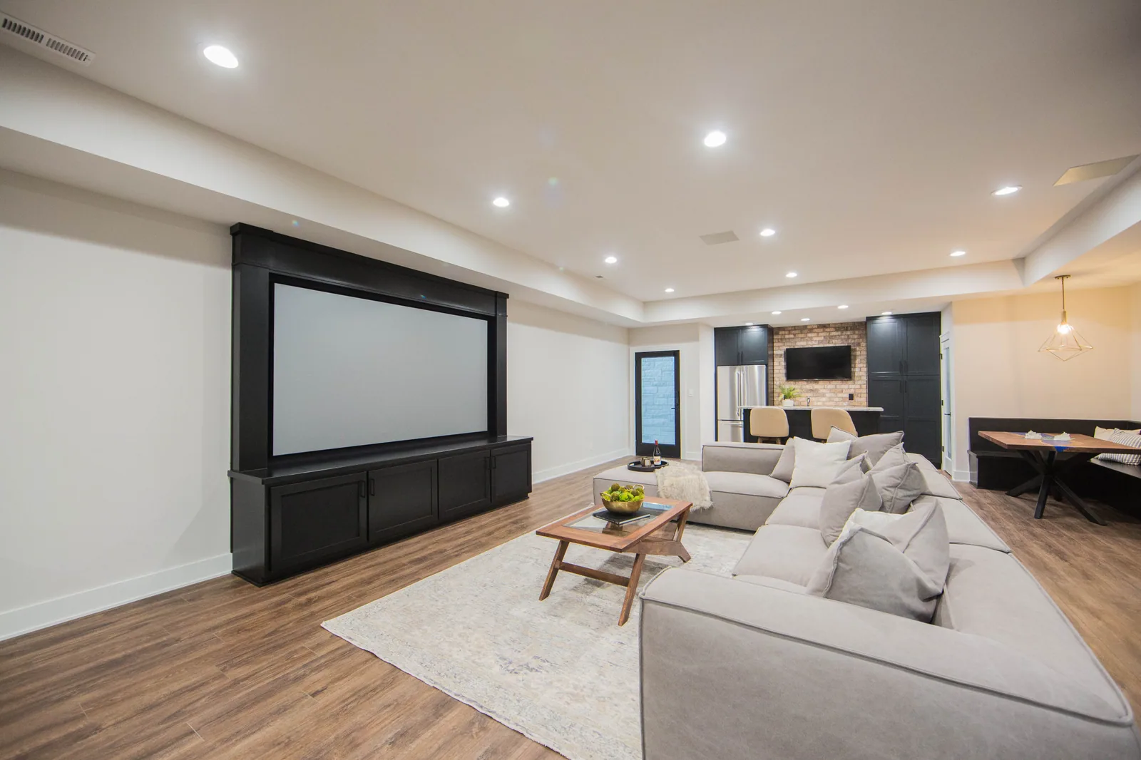 Finished basement with a projection media wall and a bar beyond