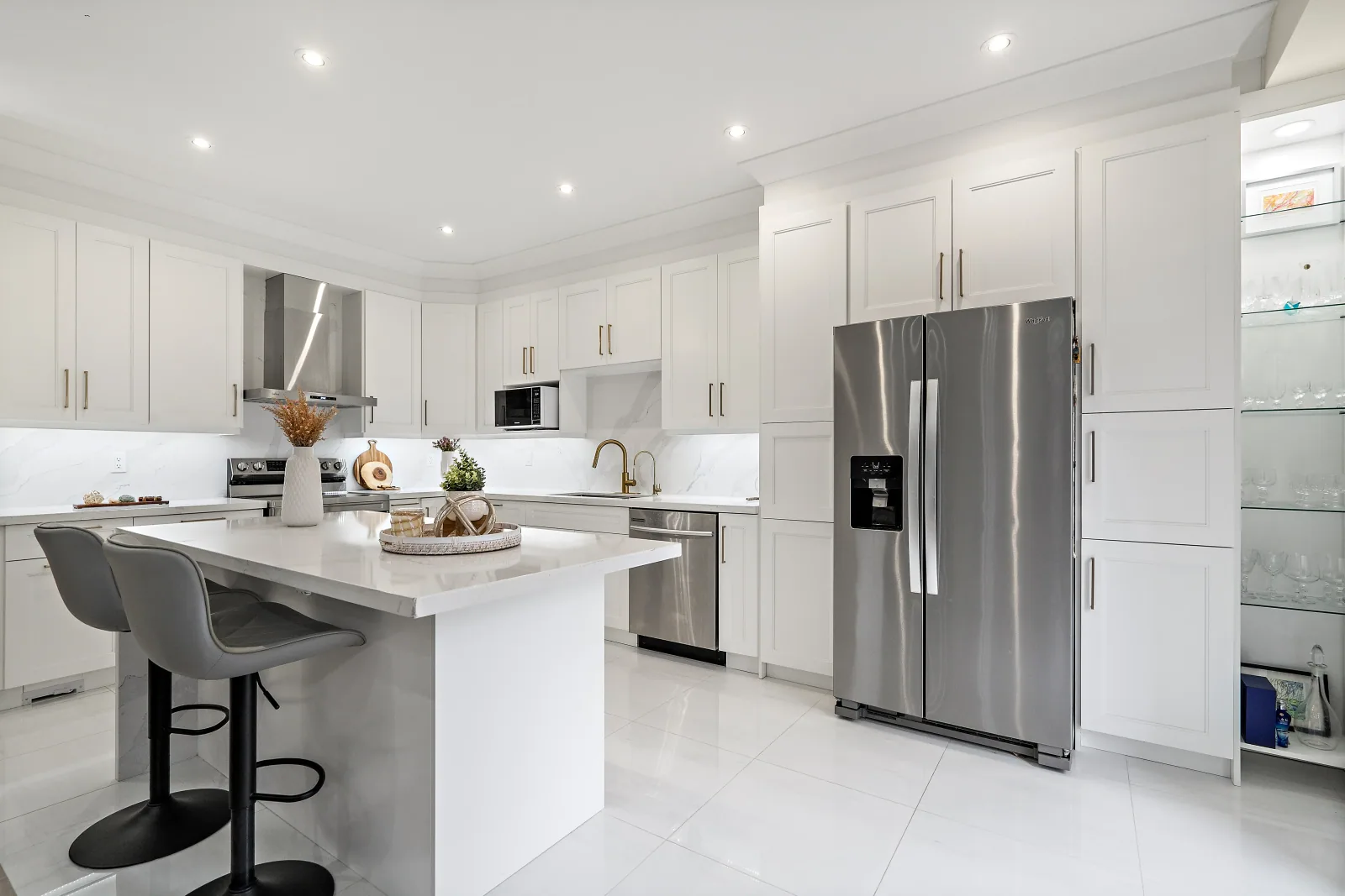 Finished kitchen with a quartz island, white cabinetry and a full pantry wall